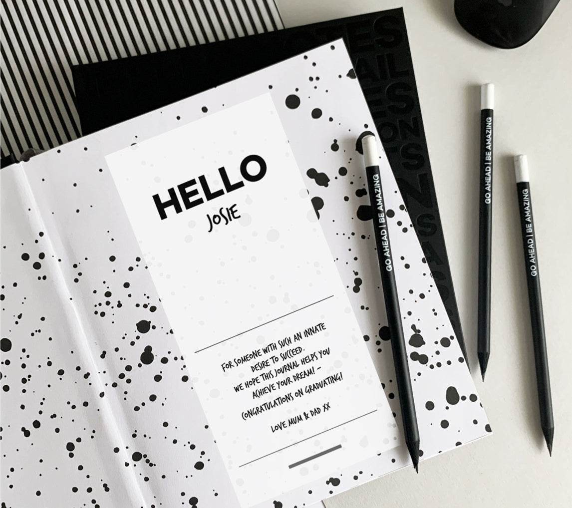 Personalised HELLO TIME planner open to a custom message page reading “HELLO Josie,” paired with black pencils that say “Go Ahead Be Amazing” — the perfect thoughtful gift for goal-getters.