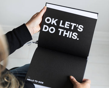 Open HELLO TIME planner showing bold white text reading “OK LET’S DO THIS.” — motivation meets minimal design for getting things done.