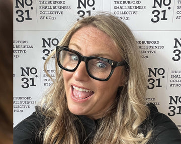 Smiling woman at The Burford Small Business Collective No.31 event, standing in front of branded backdrop, full of positive energy and personality.