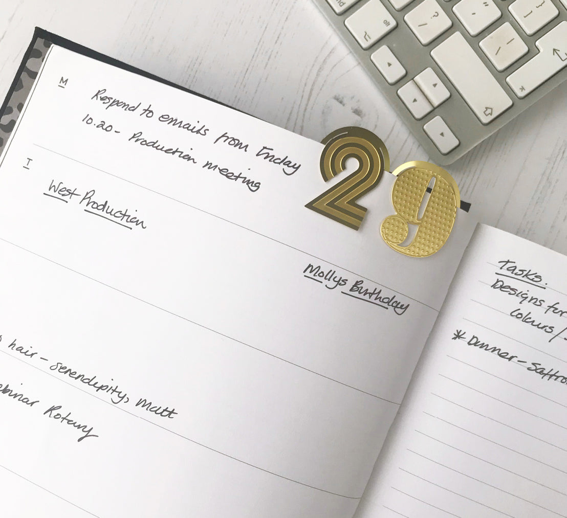 Open HELLO TIME planner showing handwritten notes and a gold number paperclip marking the date — a stylish way to stay organised and on top of your week.