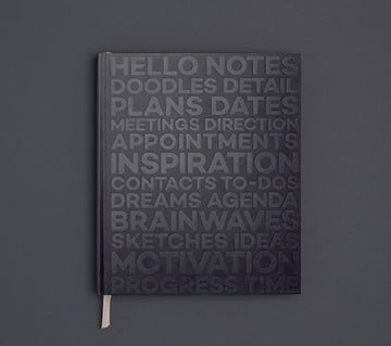 Black HELLO TIME planner with embossed motivational typography on the cover, featuring words like inspiration, plans, and motivation.