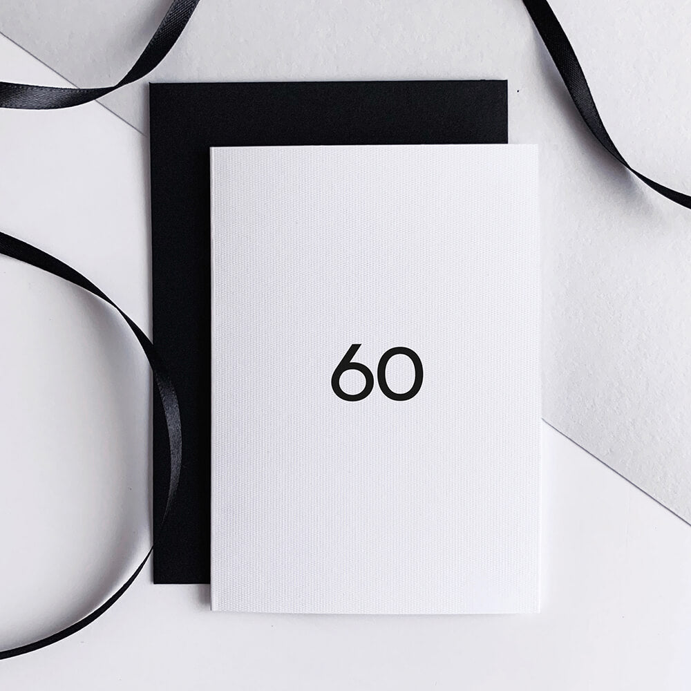 White greetings card with bold black "60" text, paired with black envelope.