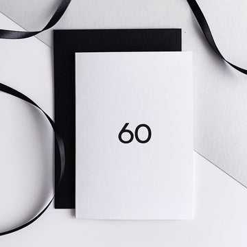 White greetings card with bold black "60" text, paired with black envelope.