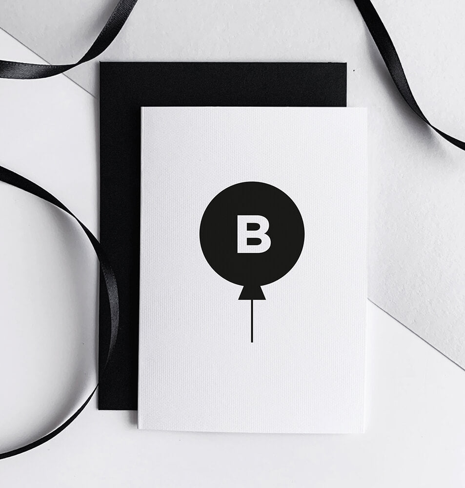 Monochrome birthday card with black balloon and letter B initial, shown with ribbon.