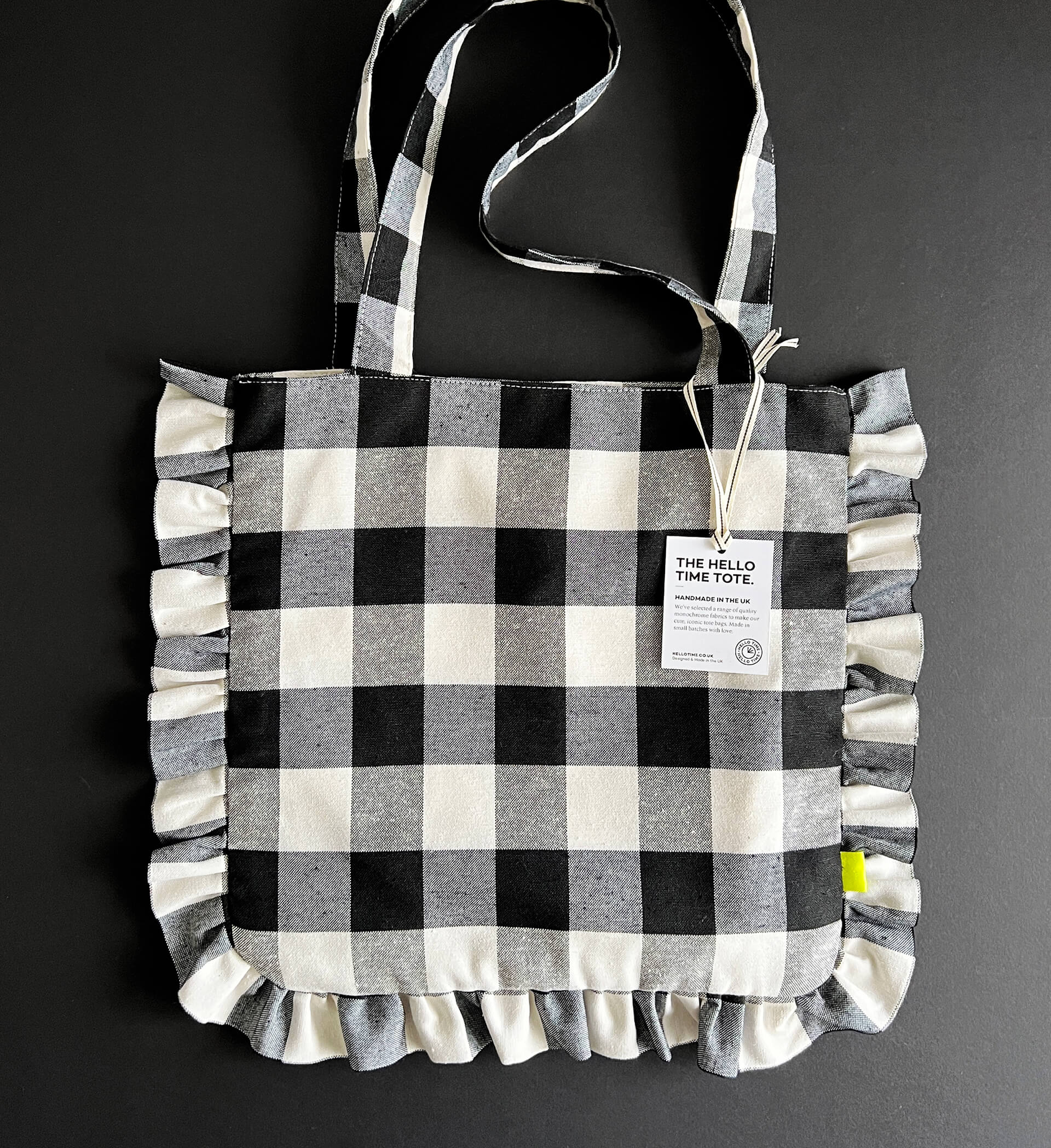 Black and white gingham ruffle tote bag with handles and product tag