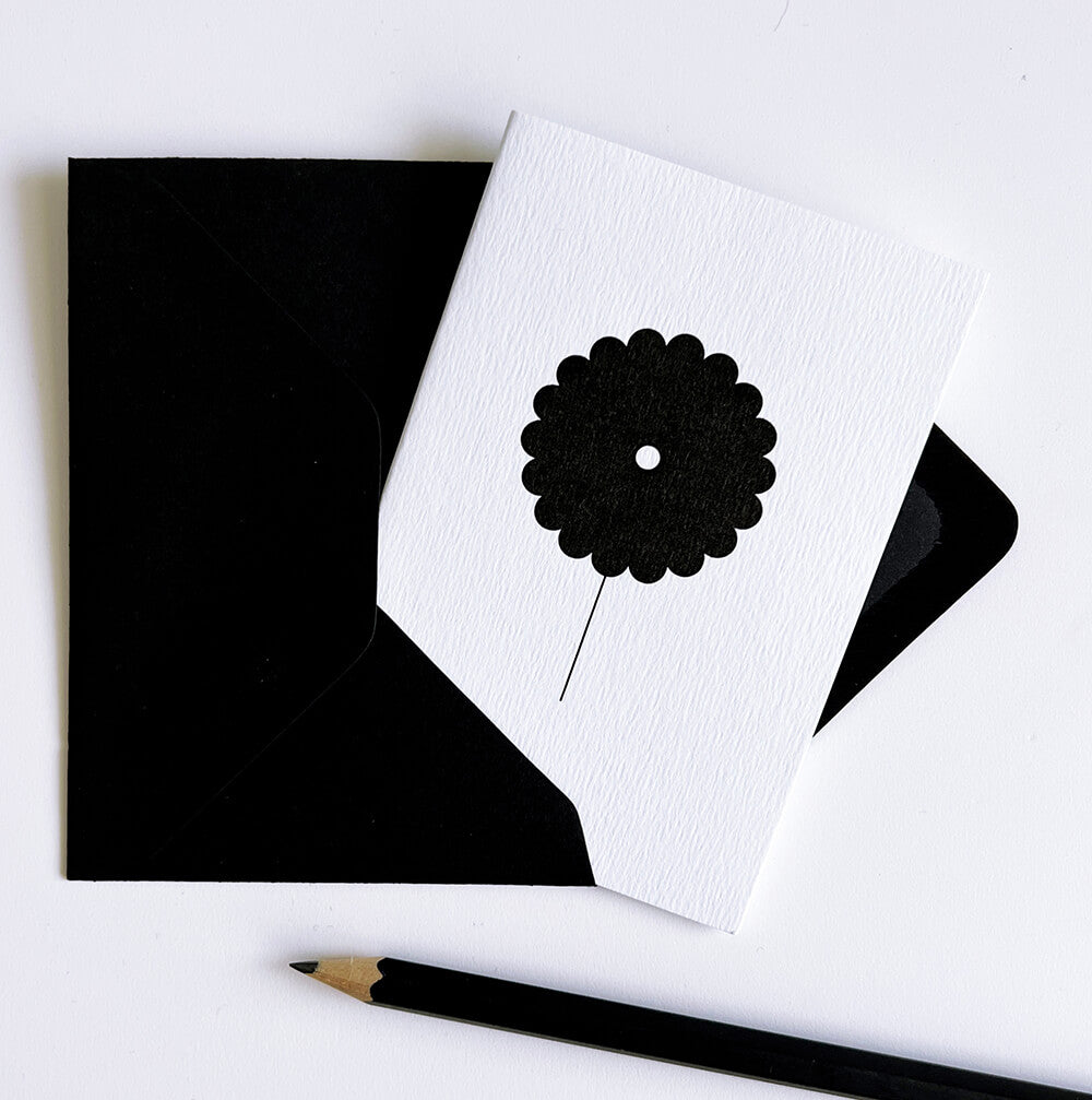 White card with bold black flower design, shown with matching black envelope and pencil.