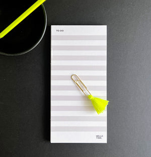 HELLO TIME braindump to-do list pad in white and grey with neon yellow tassel paperclip on dark background