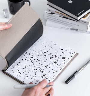 HELLO TIME clay leather notebook cover open with black ink splatter inner page and pen in hand
