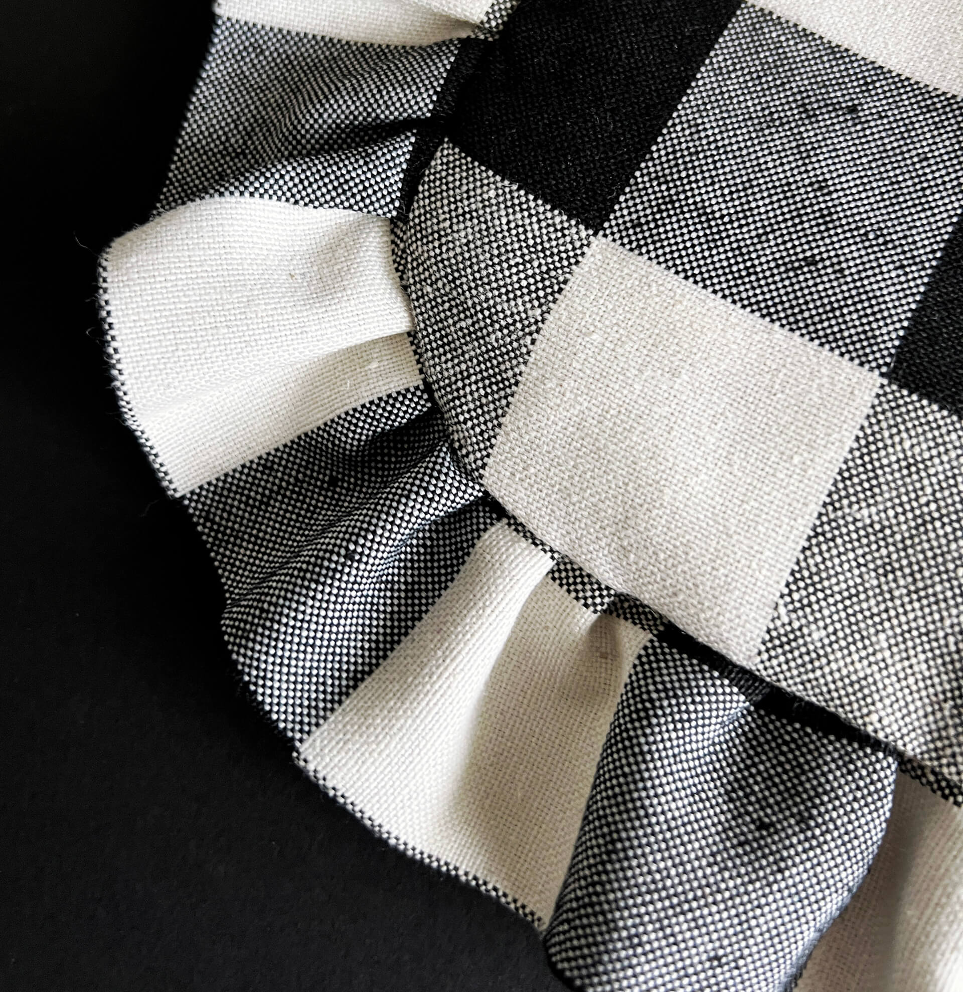 Detailed view of black and white check fabric with ruffle trim on tote bag corner