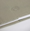 Close-up of a textured beige leather notebook with HELLO TIME logo on a white background