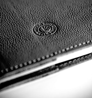 Close-up of a black leather notebook cover with HELLO TIME logo on a white background
