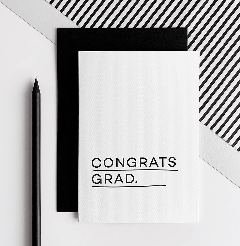White greeting card with black text reading Congrats Grad, paired with a black envelope.