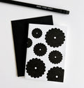 White card with bold black floral bunch design, paired with black envelope and pencil.