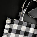 Top corner of black and white ruffle tote bag with gingham pattern and fabric handles

