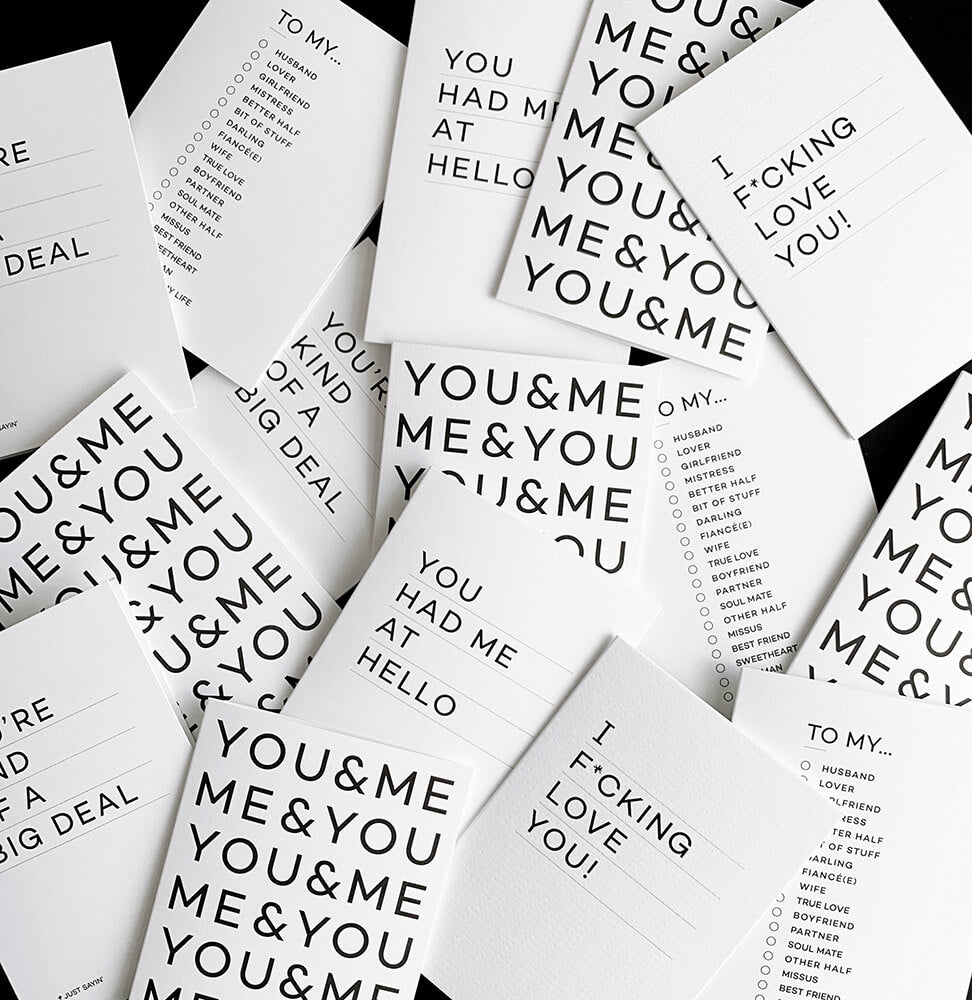 Flat lay of multiple monochrome typographic cards with bold black text messages on white card.