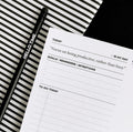 Black HELLO TIME pencil and daily desk pad with quote and to-do list on striped background