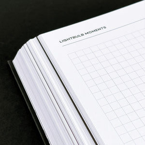 Close-up of HELLO TIME planner open to “Lightbulb Moments” page with light grey dot grid layout on white paper