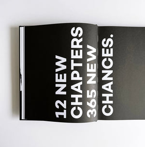 Open HELLO TIME planner showing bold quote: 12 new chapters, 365 new chances in white text on black pages