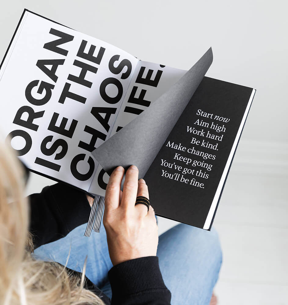 Person holding open HELLO TIME planner showing bold black and white motivational typography pages