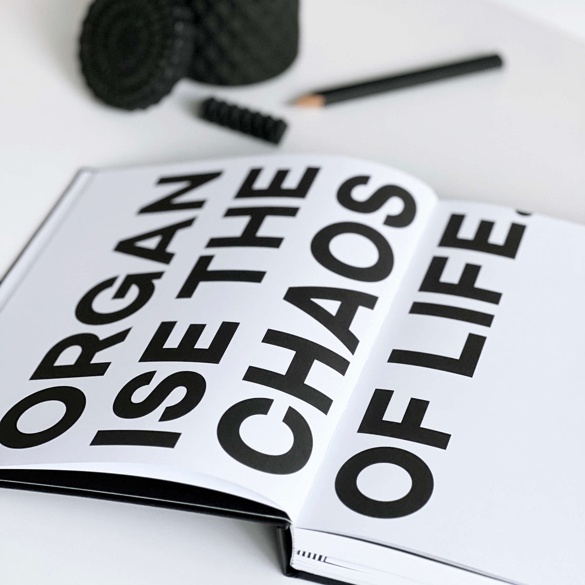 Open black-and-white HELLO TIME planner with bold "Organise the chaos of life" page, pencil and candle décor nearby.