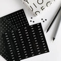 Black HELLO TIME planner stickers with months, numbers, and symbols on white desk