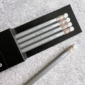 HELLO TIME silver pencils with motivational time quotes and white erasers in black sleeve on grey textured background