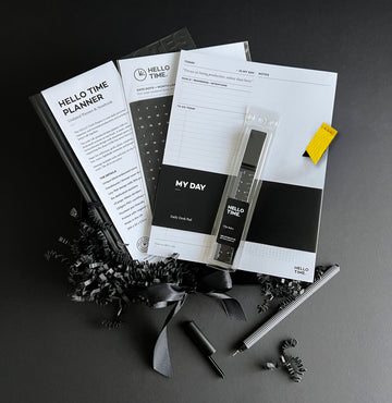 Black and white HELLO TIME stationery gift box with undated planner, diary sticker pack, notepad, ruler and pen, styled on black background