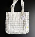 Flat-lay of white grid tote bag with black lines and ruffle edges