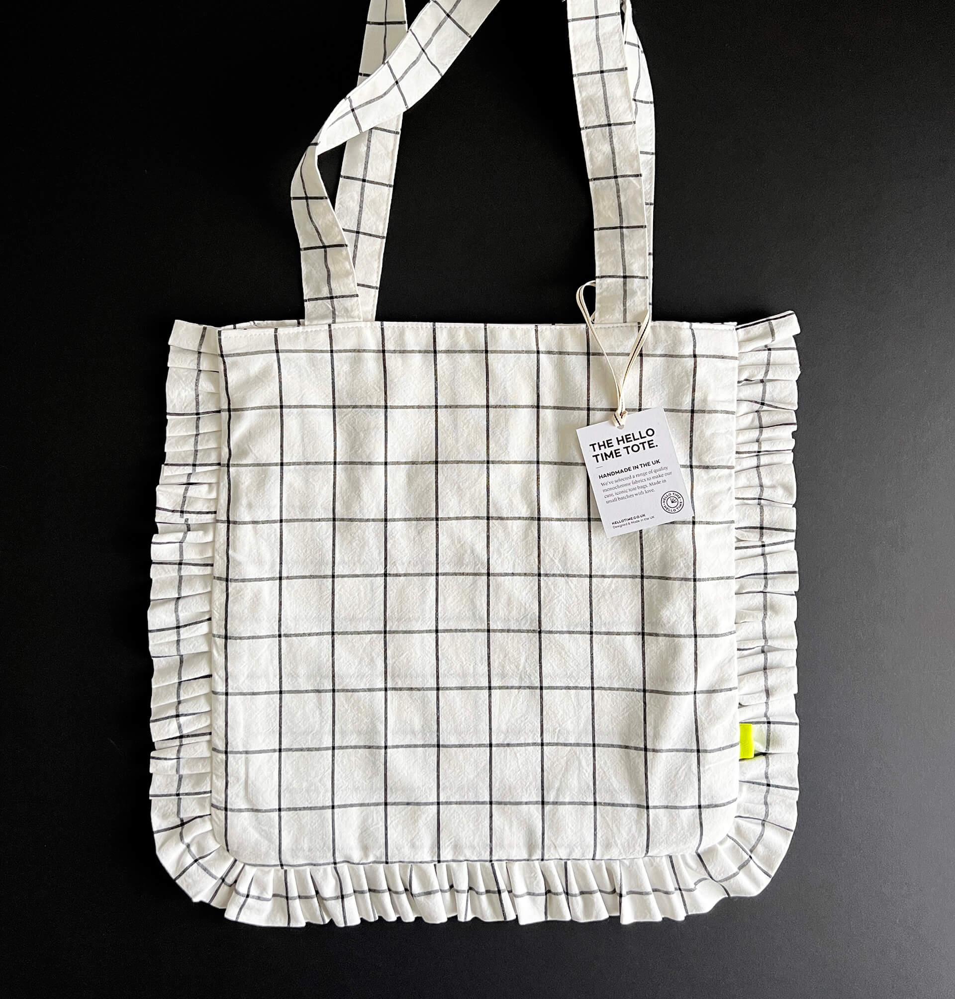 Flat-lay of white grid tote bag with black lines and ruffle edges