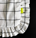 Close-up of ruffled corner of grid tote bag with yellow brand tag