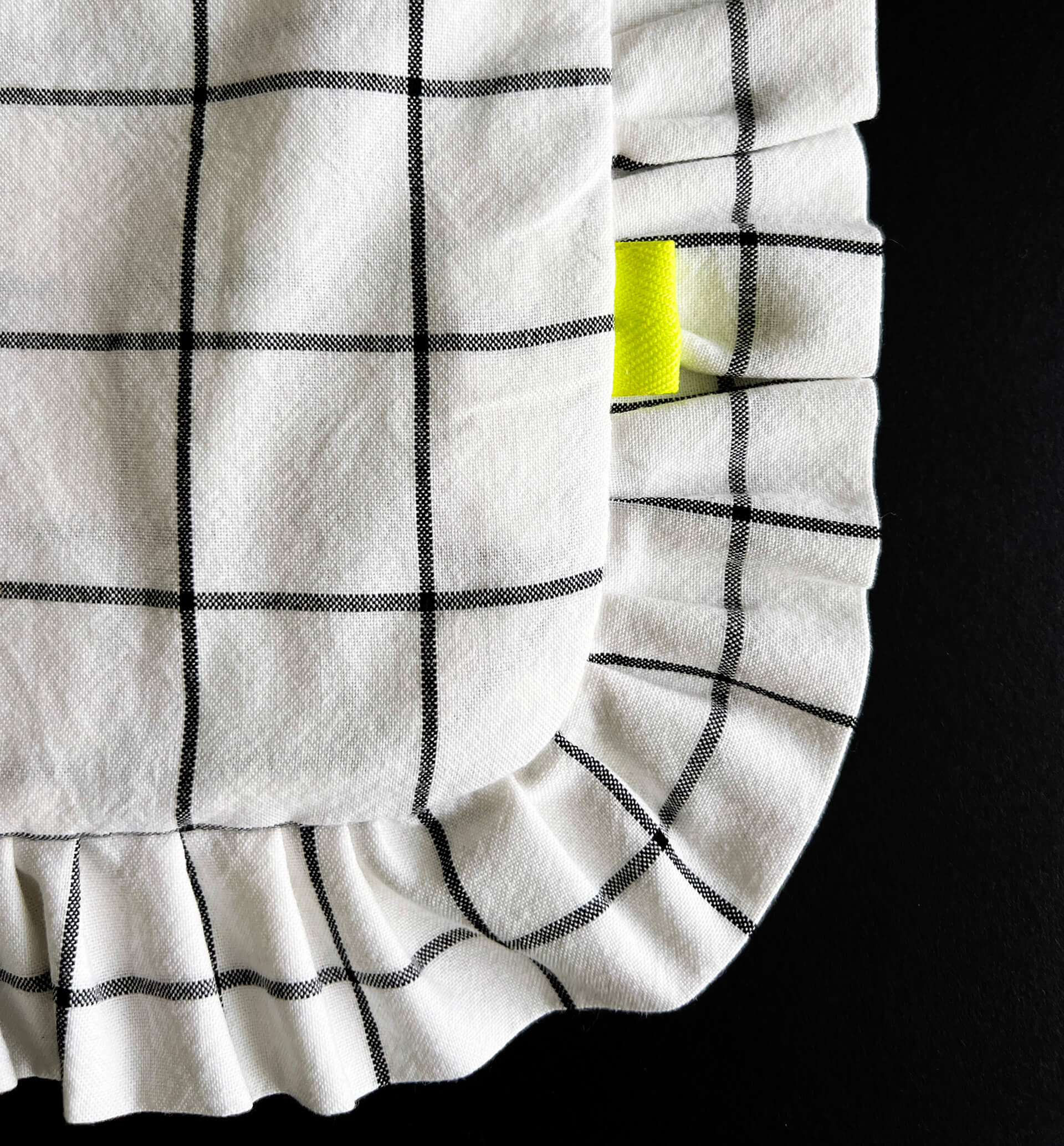 Close-up of ruffled corner of grid tote bag with yellow brand tag