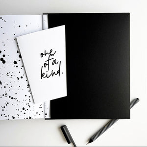 Planner open to black pocket with “one of a kind” greetings card and striped black fineliner pen
