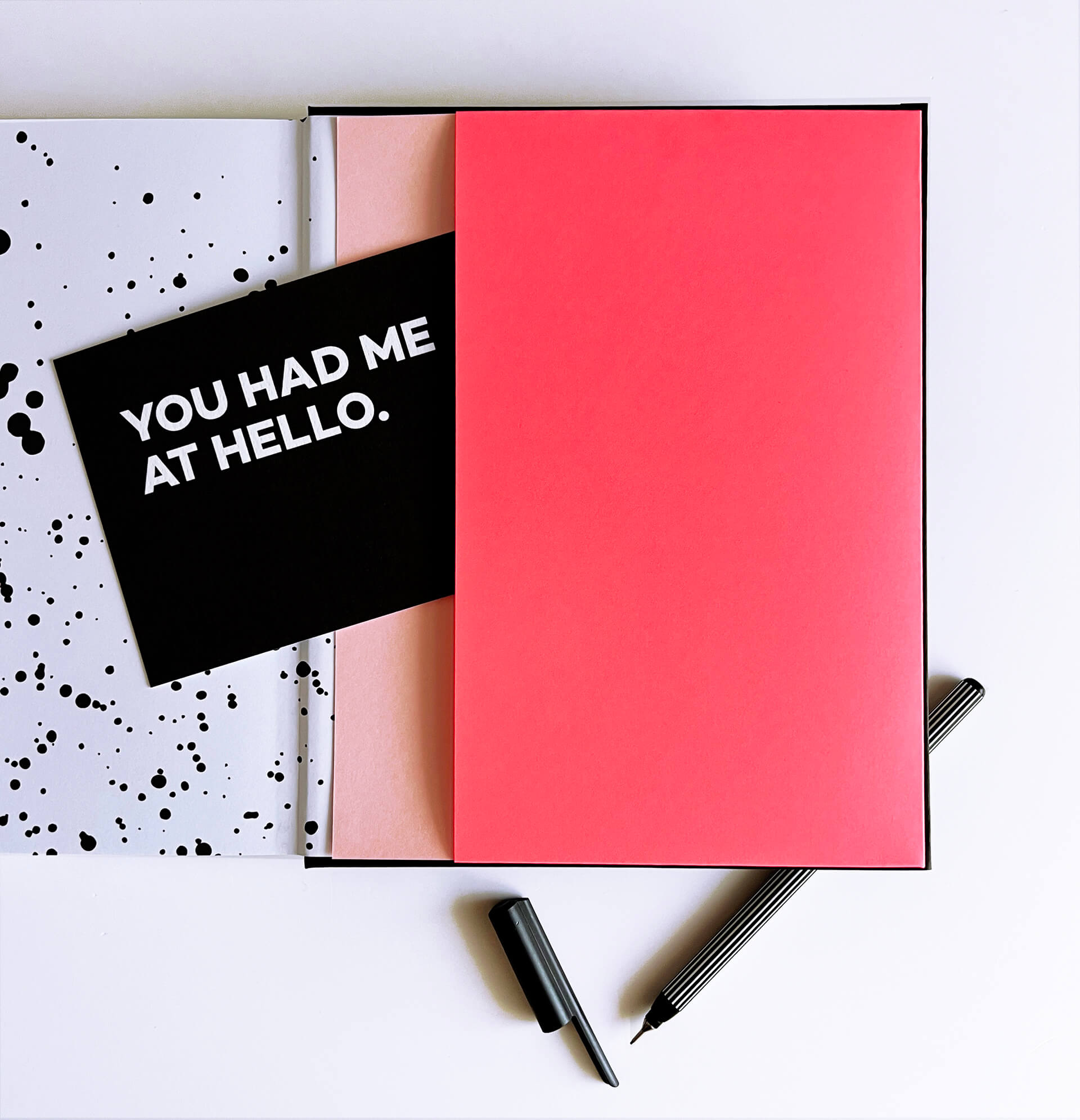 Planner open to neon pink pocket with black postcard and striped fineliner pen