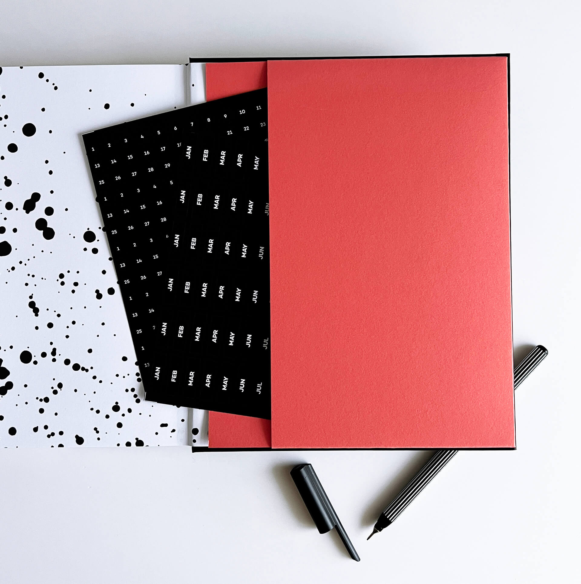 Open planner showing peachy coral pocket with black diary stickers and pen