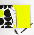 Open planner showing neon yellow pocket, calendar bookmark and black pen with striped barrel