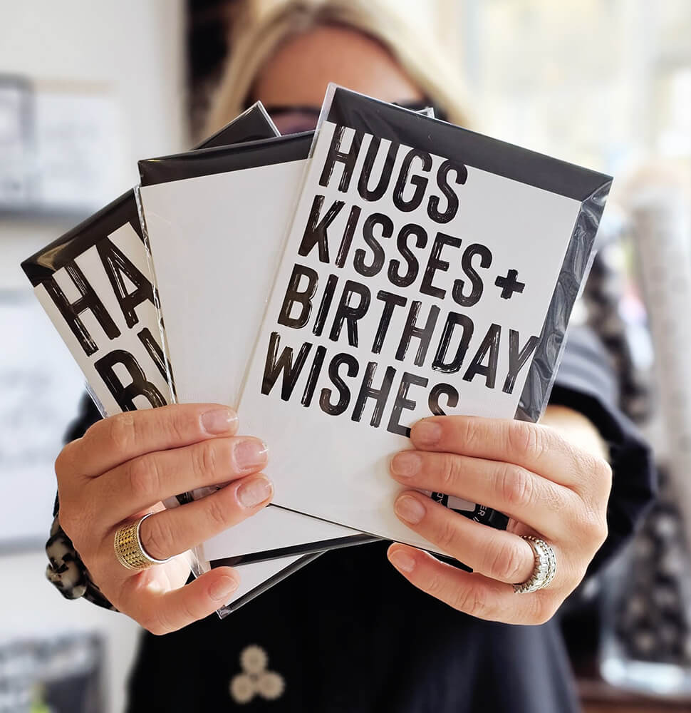 Hand holding Hugs Kisses Birthday Wishes card in monochrome style