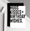 White birthday card with bold black Hugs Kisses Birthday Wishes text and black envelope