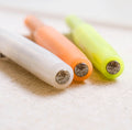 Three Kaweco Sport fountain pens in white, orange, and lime with chrome logo tops, shown angled on a fabric surface