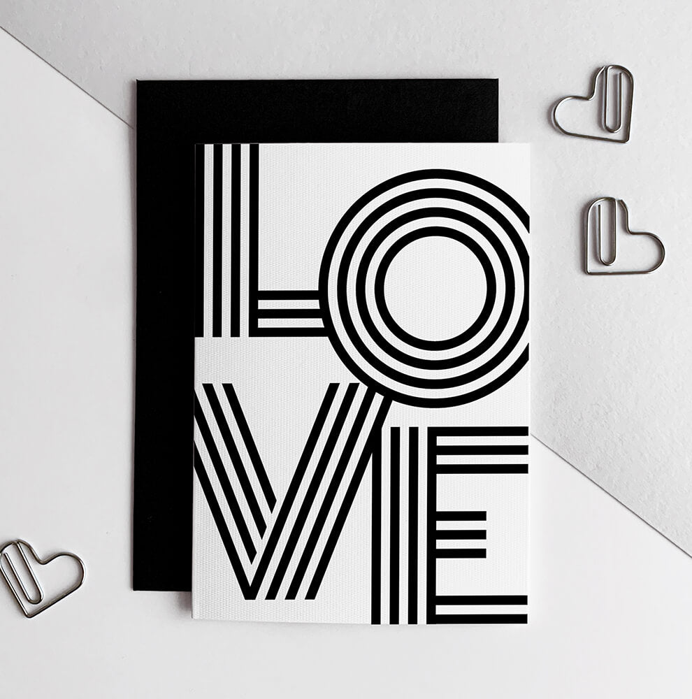 Monochrome LOVE greetings card with bold black typography on white card and black envelope.