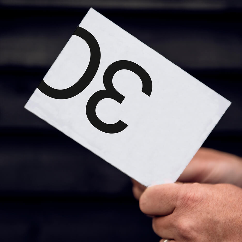 Person holding white 30th birthday card with bold black 30 on cover.