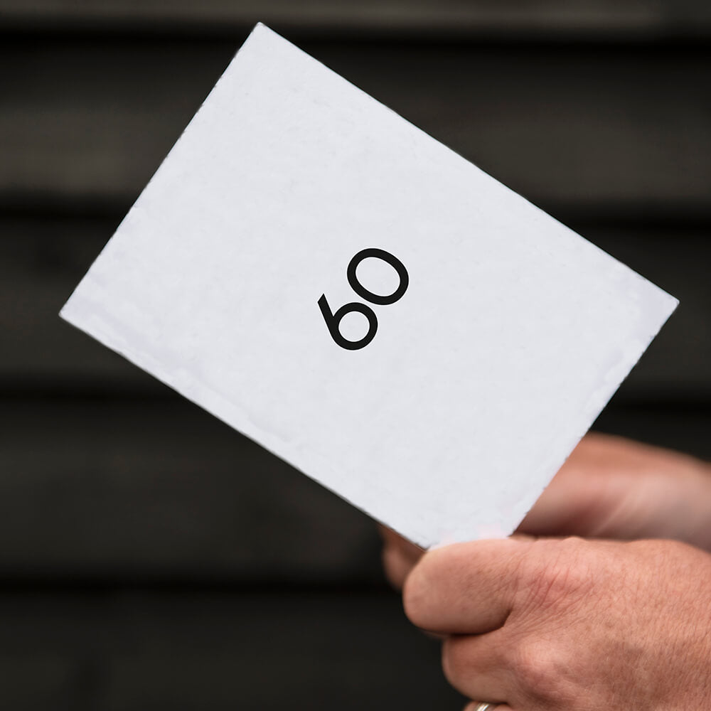 White greetings card with bold black "60" text, paired with black envelope.