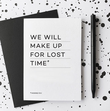 White greetings card with “We will make up for lost time” text, black envelope and pen.