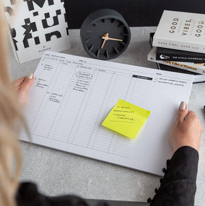 Person using Hello Time My Week Desk Pad with handwritten notes and a yellow sticky note