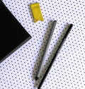 Yellow page marker, striped fineliner, black pencil and notebook corner from stationery gift set on dotted background