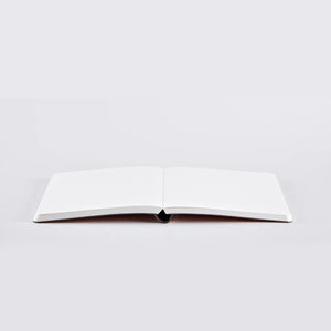 Nuuna Rose Gold notebook lying flat open with visible dotted pages.