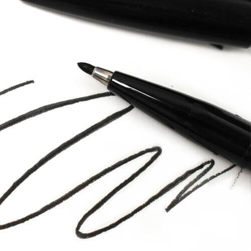 Pentel black sign pen writing black ink strokes on white paper