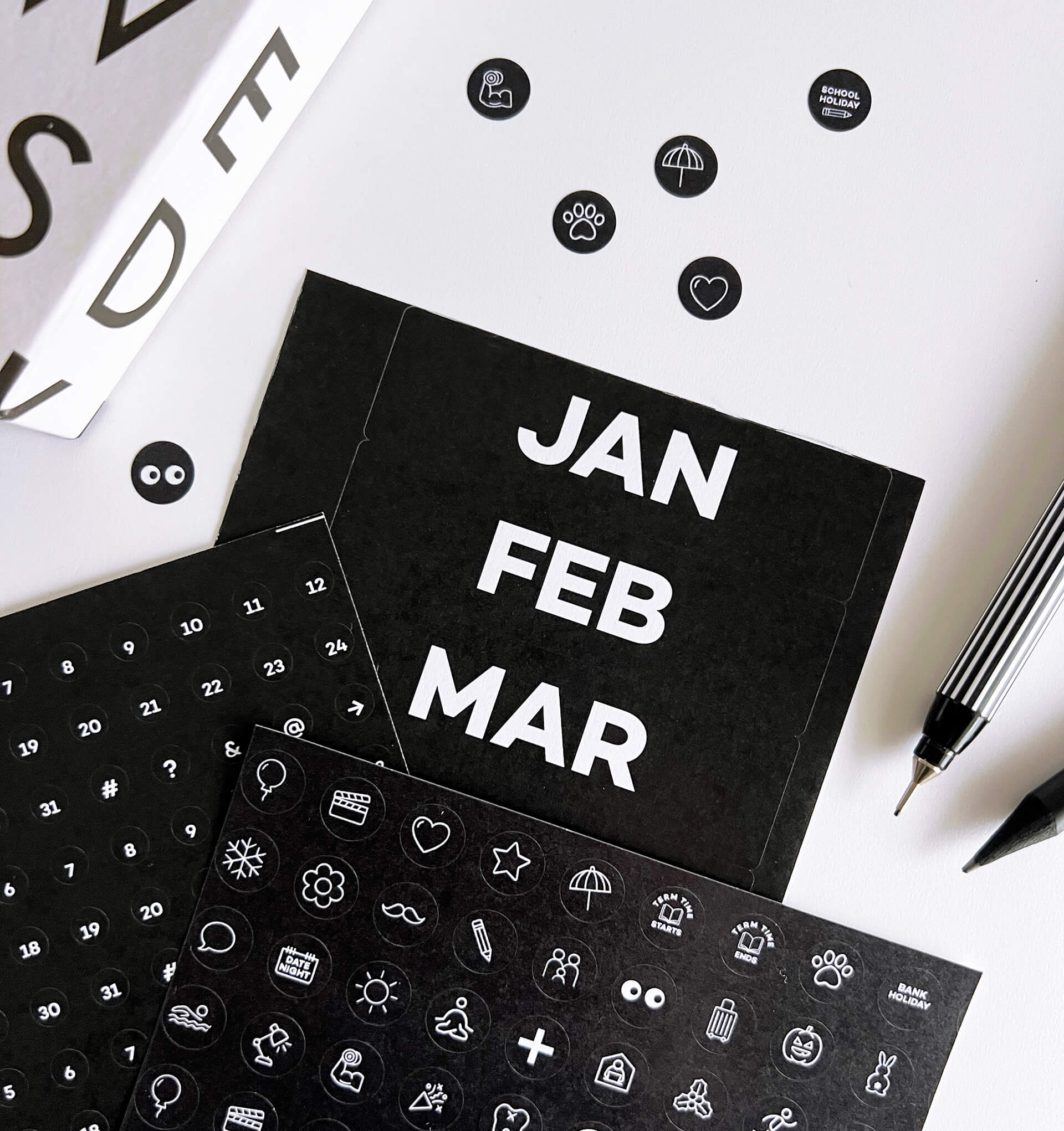 Black sticker sheets showing months, numbers, and white icon activity markers
