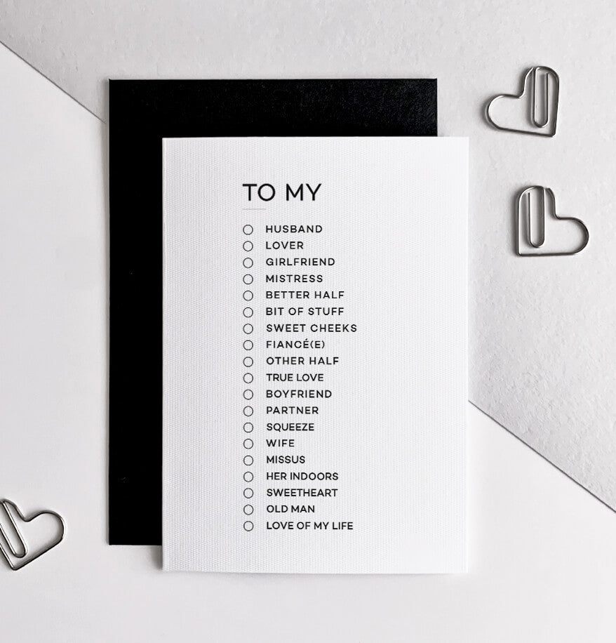 Monochrome anniversary card with text "To My" and checklist of partner titles, black envelope behind.