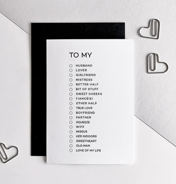 Monochrome anniversary card with text "To My" and checklist of partner titles, black envelope behind.