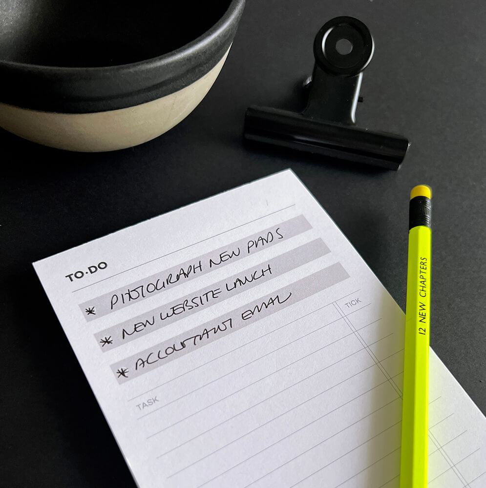 HELLO TIME Top 3 To-Do List Pad with handwritten tasks, yellow pencil, black clip and ceramic bowl on desk